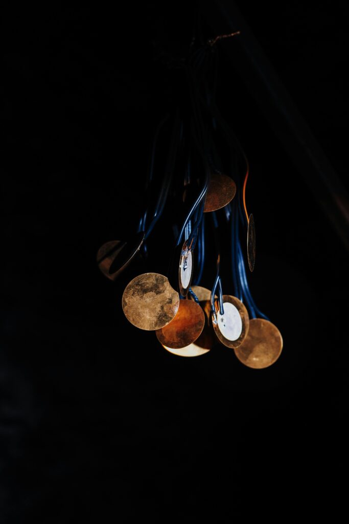Close-up of medals hanging in darkness, showcasing their reflective surfaces and vibrant colors.